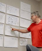 A participant points out details of a sketch that is posted on the wall.